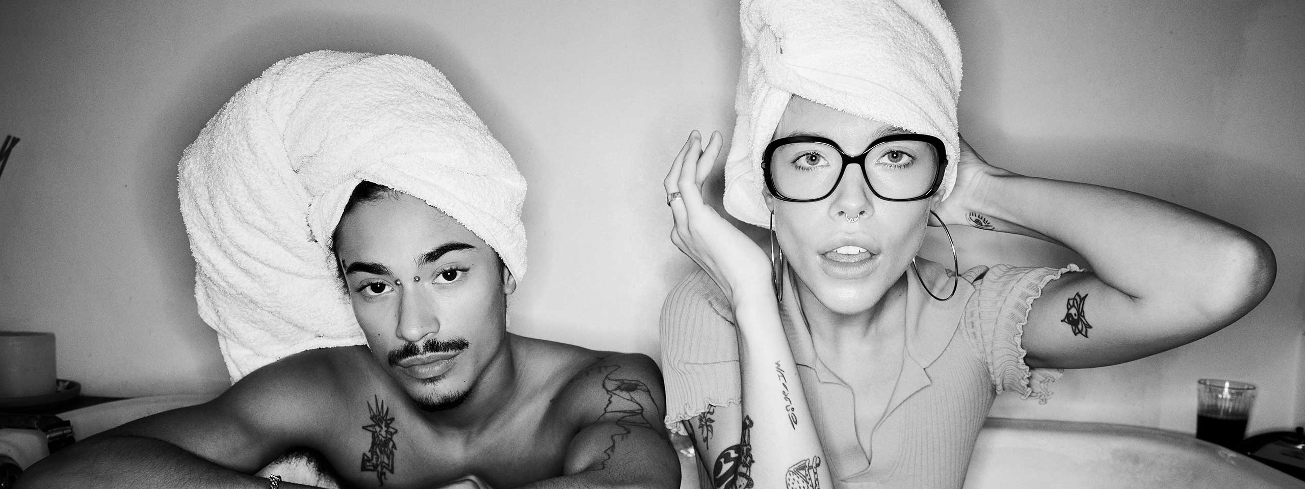 Metropolitan: Mann und Frau sitzen mit Handtüchern auf dem Kopf in einer Badewanne. Die Frau trägt eine Brille